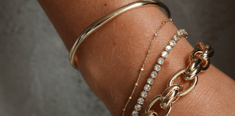 A silver chain bracelet with a single pearl.