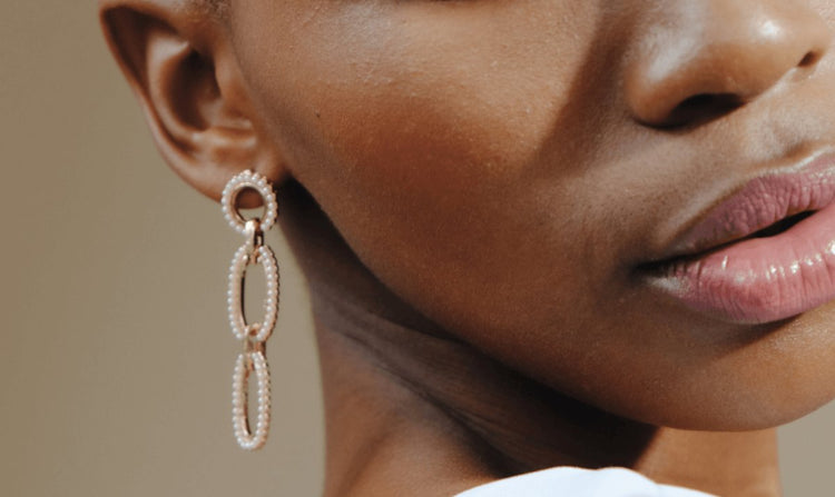 Close-up of a woman's face and dangling pearl earrings.