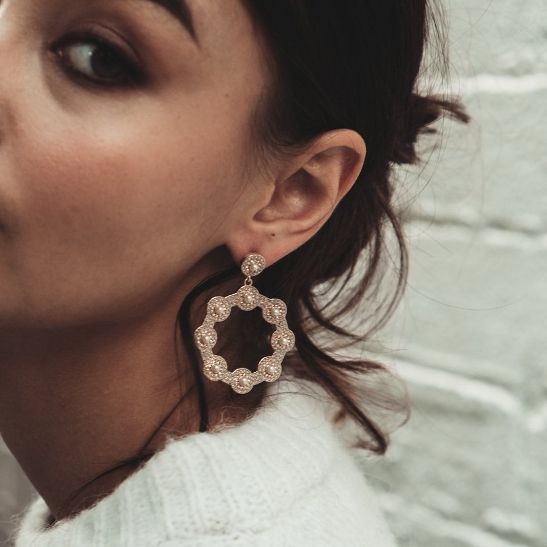 Close-up of a woman wearing a large, jeweled, Cream Crystal Hoop Earring.