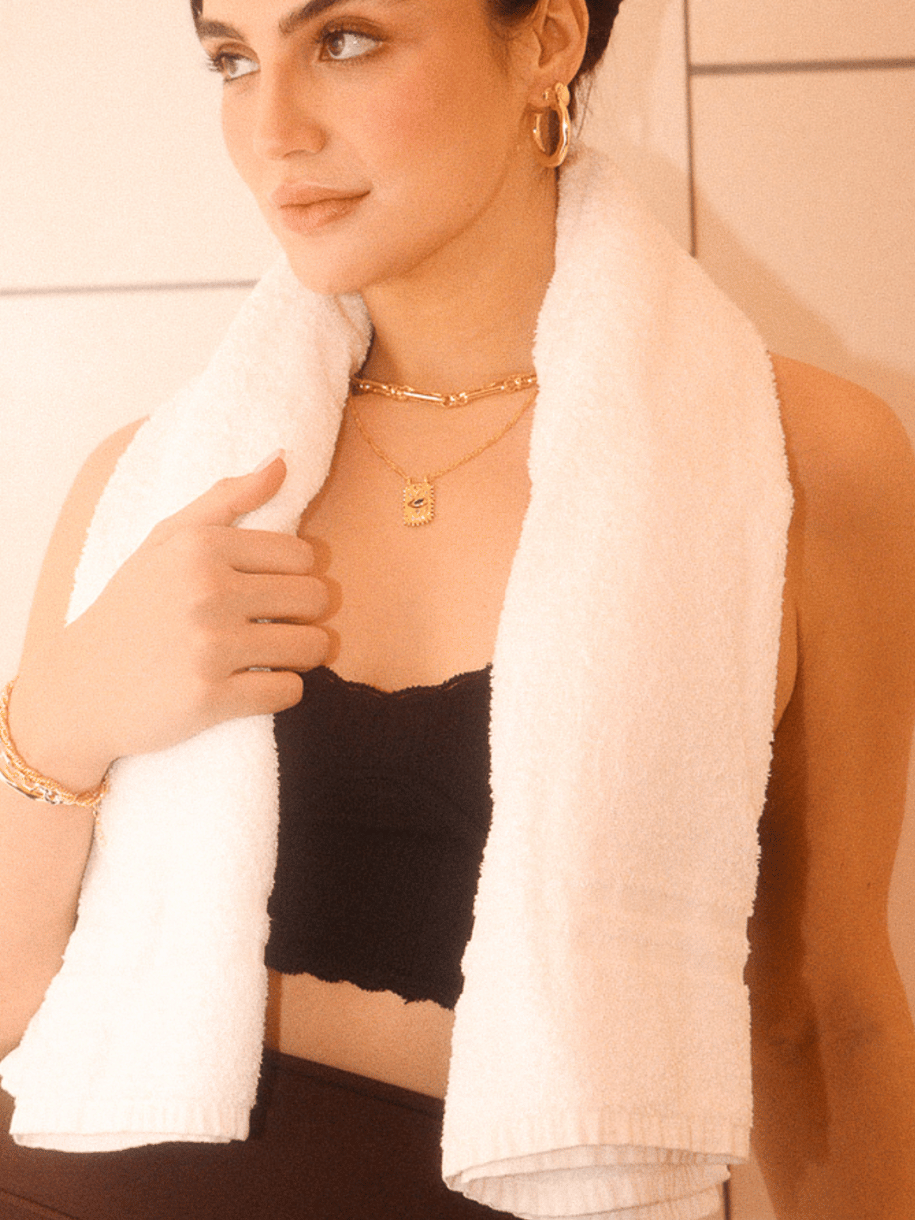 A person with a towel draped around their neck wears an Omni Evil Eye Coin.