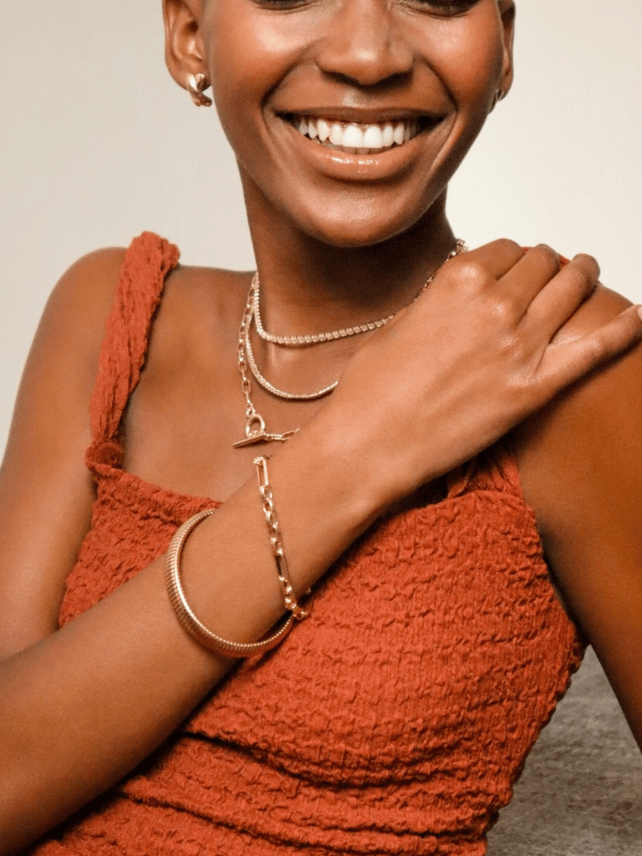 Smiling woman with Chunky Link and Round Hook Toggle jewelry wearing an orange textured top.