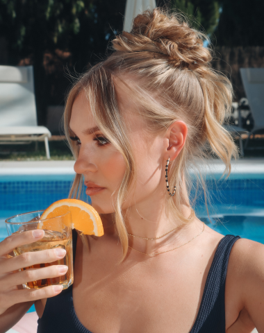 Woman with a drink by the pool.