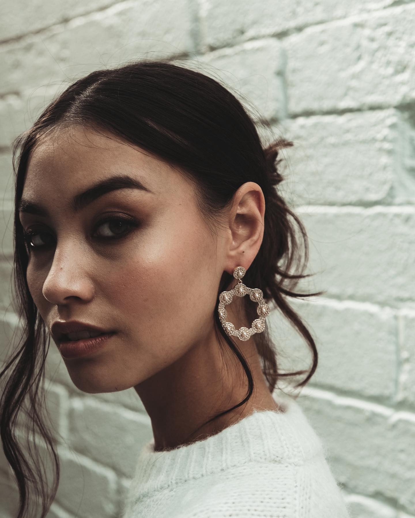 Close-up of a woman with dark hair and a white sweater, wearing Cream Crystal Hoop Earrings.