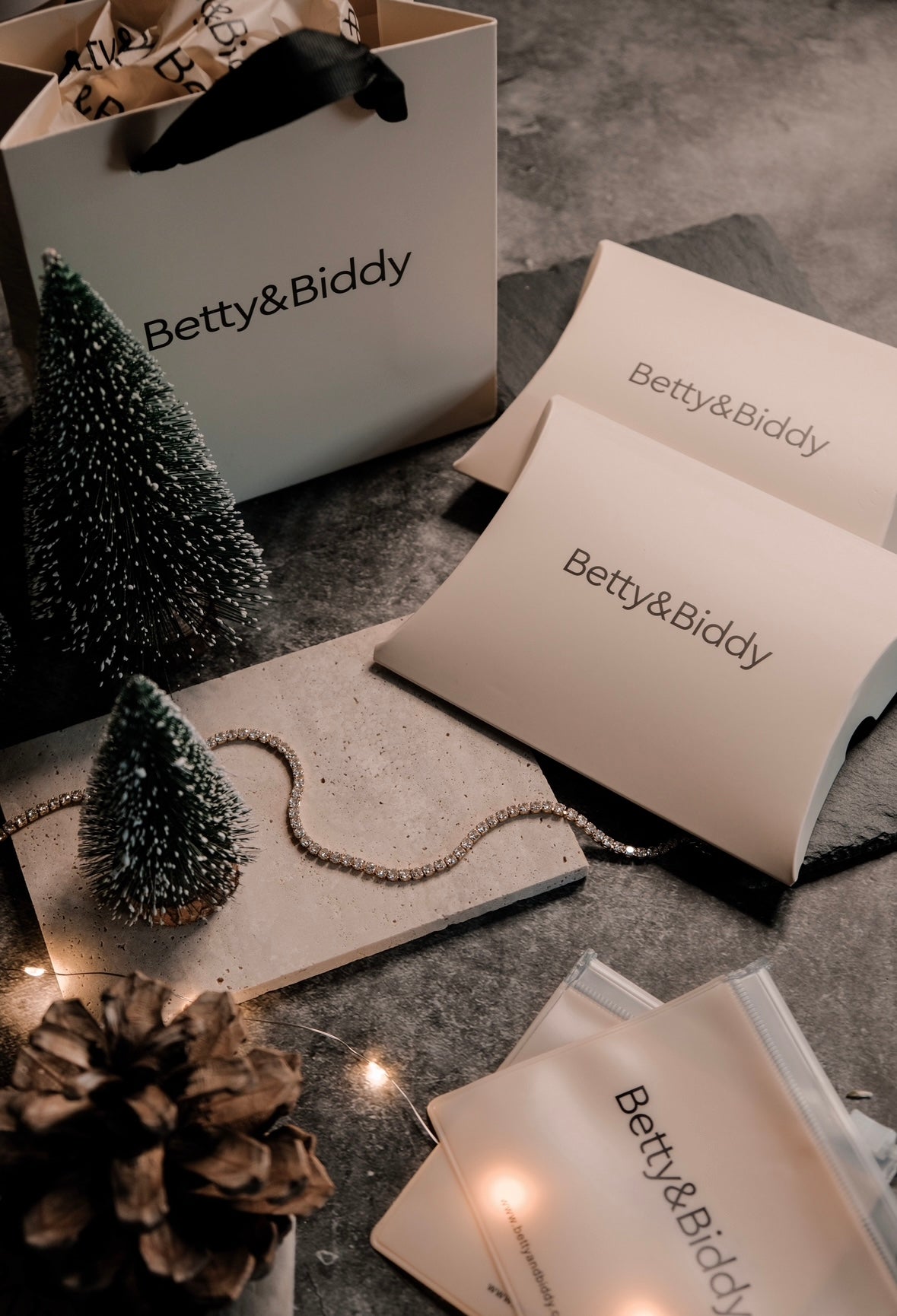 A still life featuring Gift Wrapping, a tennis bracelet, and miniature Christmas trees.