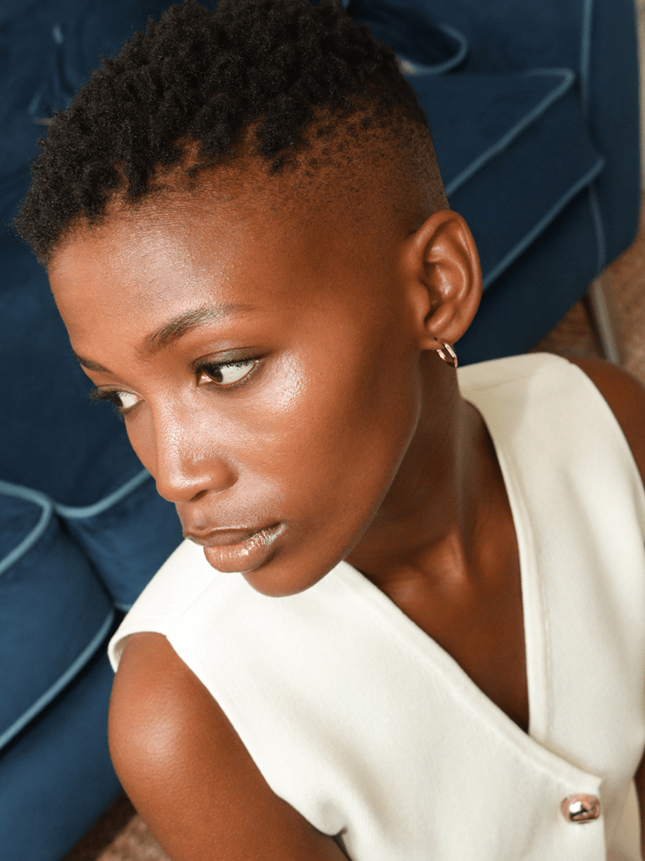 Close-up of a woman wearing The Dented Huggie Hoop earrings, hoop earrings, and a white top, looking away.