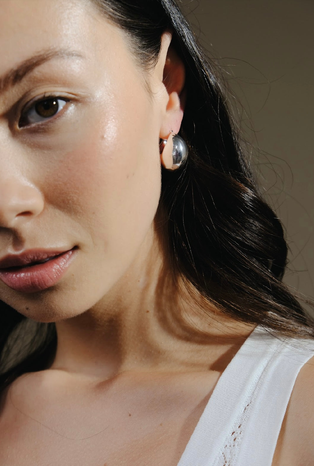 Close-up of a woman's face and neck, featuring a Silver Twilight Moon Hoops earring.