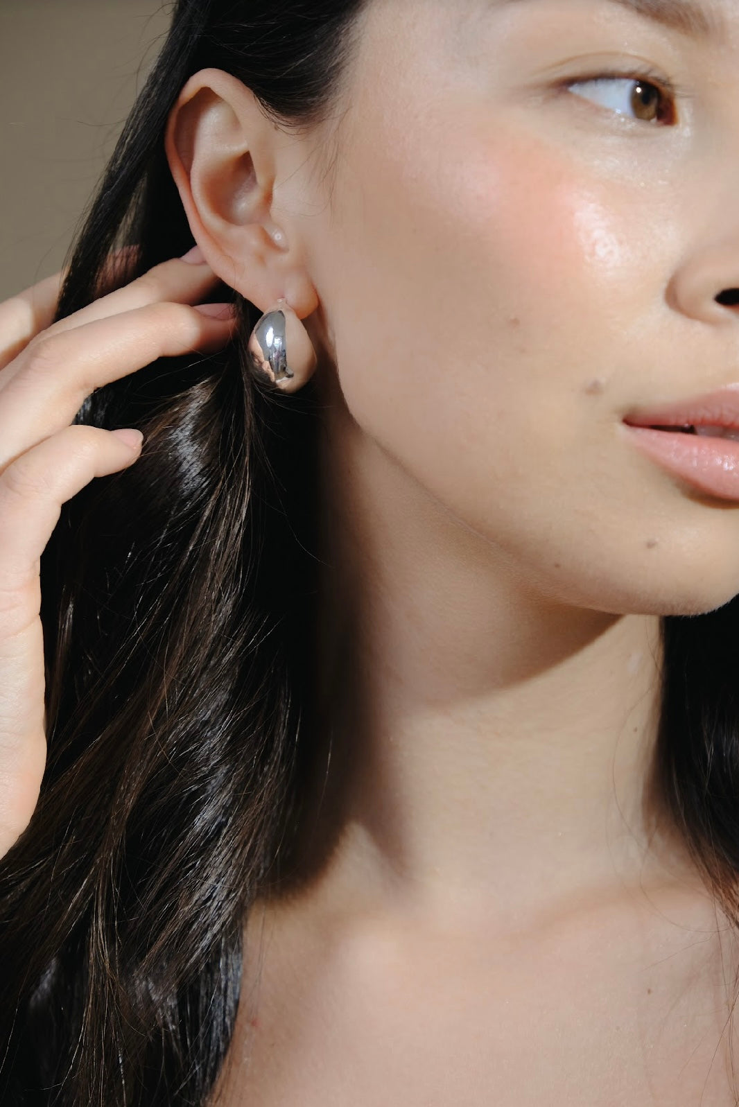 Close up of a woman with dark hair wearing Silver Twilight Moon Hoops.