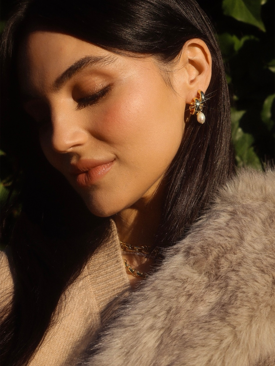 Close-up of a woman with dark hair wearing The Chunky Pearl Hoop jewelry and a fur-like garment.