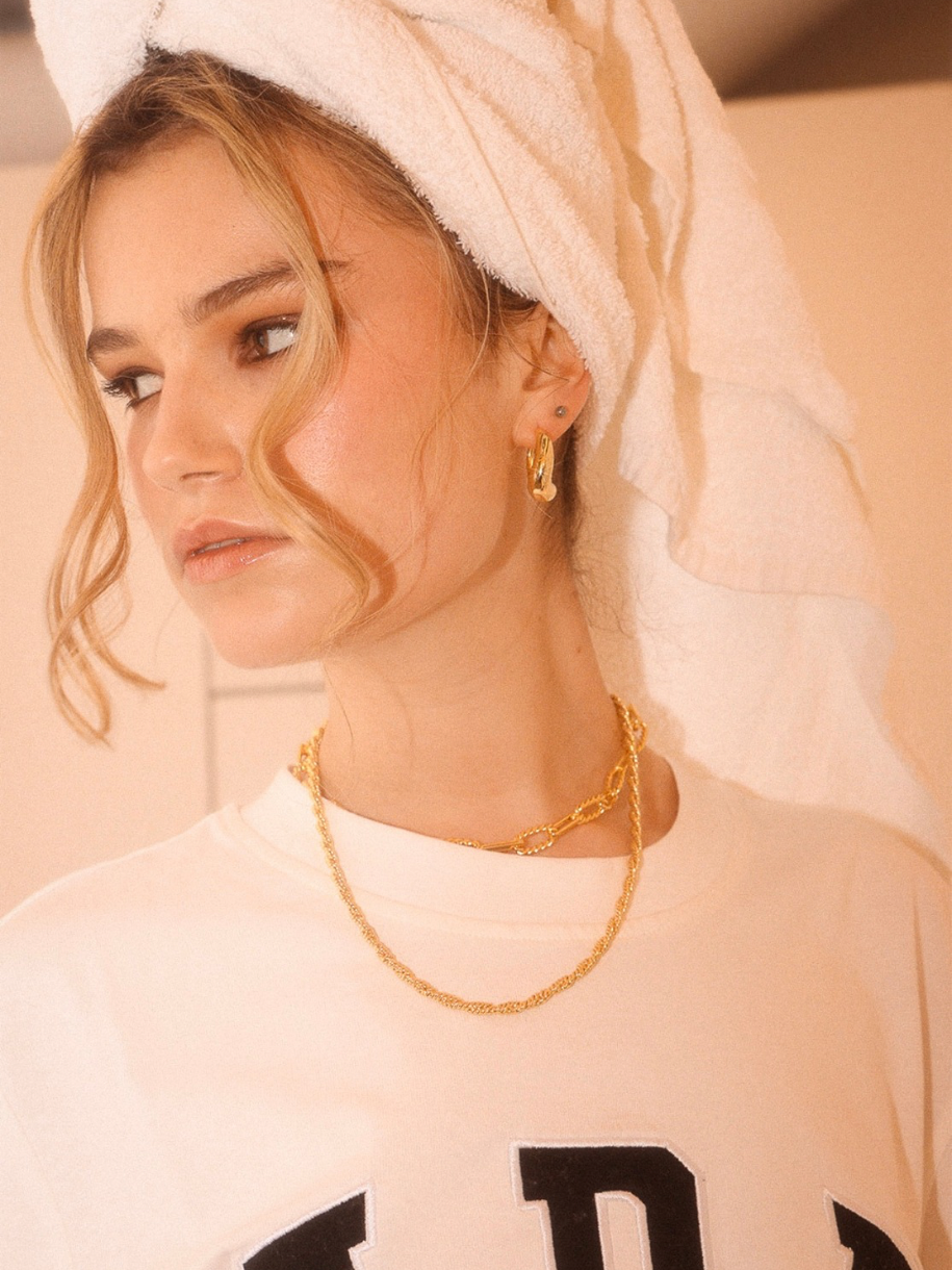 A blonde woman with a towel wrapped around her head wears Align Hoops and a gold necklace and earring.