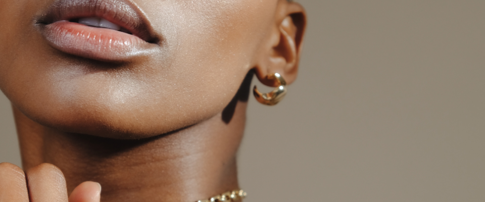 Close-up of a person's face and neck wearing gold jewelry.