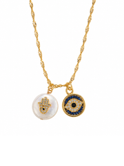 A gold chain necklace featuring two circular evil eye and hamsa hand pendants, one with a white pearl-like background and the other with a blue and gold design, set against a plain white background.