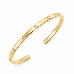 A polished yellow gold open cuff bracelet with five small, clear round-cut gemstones spaced evenly along the front, set against a plain white background.