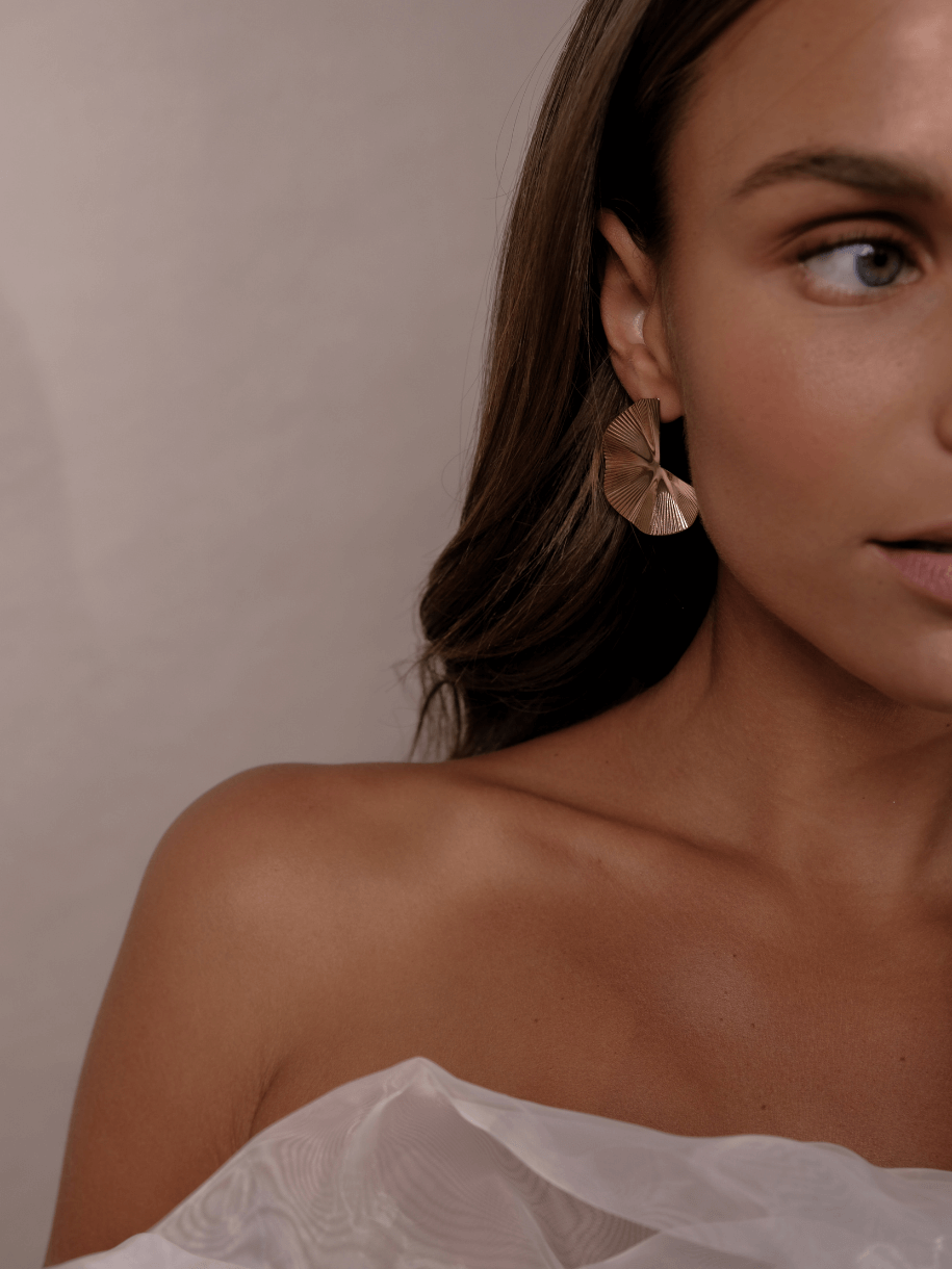 Close-up of a woman wearing a Bridal Gold Fleur earring.