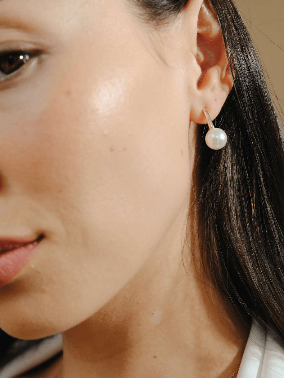 Close-up of a woman's face and neck, featuring a Bridal Gold Bar Pearl earring.