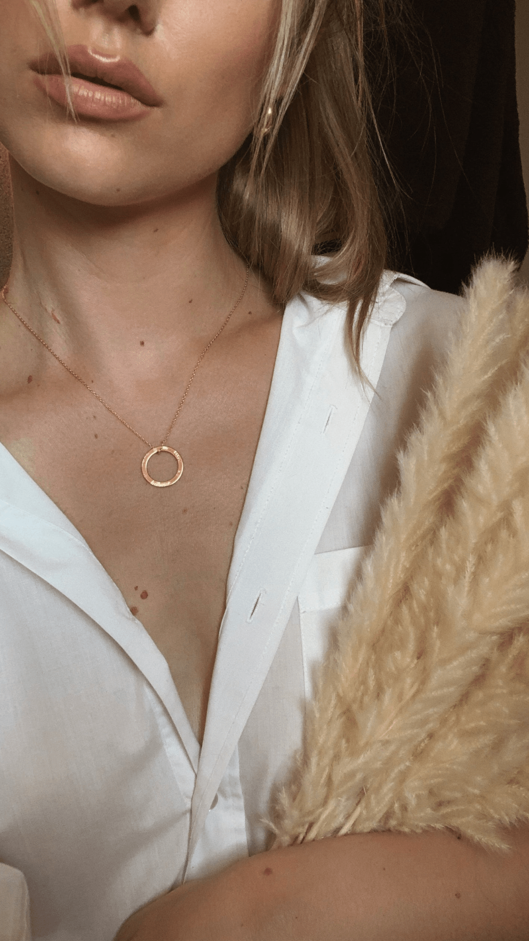 A person wearing a white shirt and An té a bhíonn siúlach, bíonn scéalach - ROUND DISC SILVER gold circle pendant.