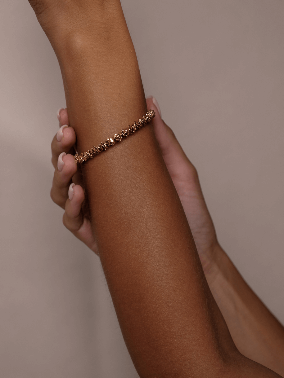 A wrist adorned with a textured gold Jagged Bracelet.