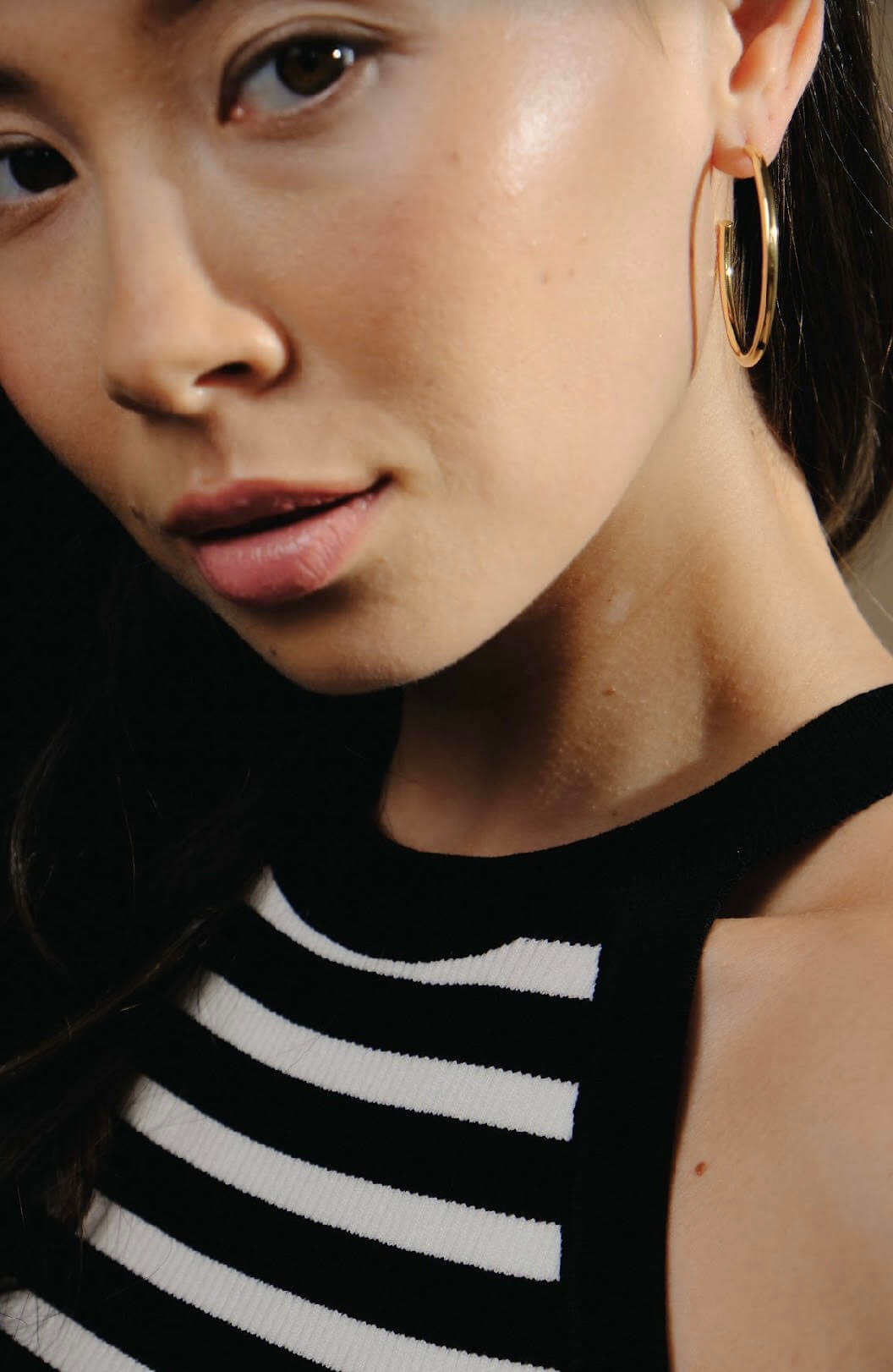 Close-up of a woman wearing The Iconic Gold Hoop - Large and a striped top.