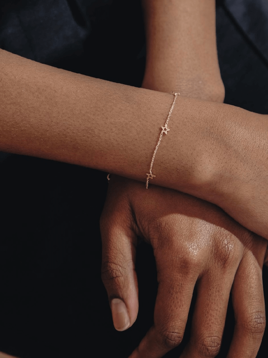 A person's crossed arms wearing an Open Star Bracelet with star charms.