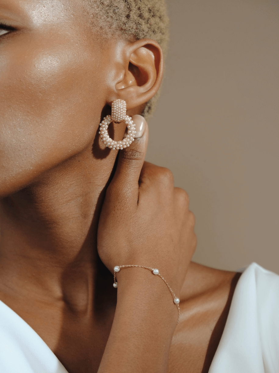 Close-up of a person with pearl earrings and a Bridal Pearl Row Bracelet - Gold.