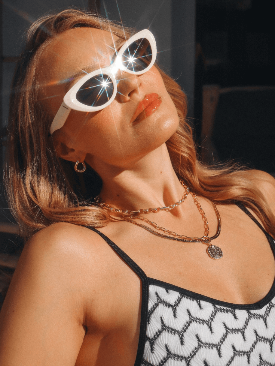 A person in sunglasses and layered Triple Link Chunky Necklaces reclines in sunlight.