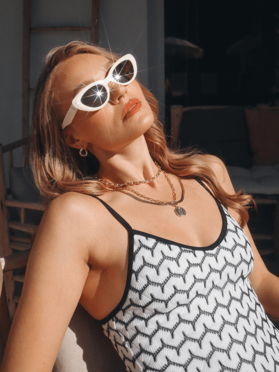 Woman in sunglasses and patterned tank top wearing a Triple Link Chunky Necklace basking in sunlight.