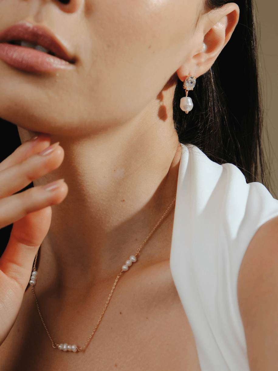 Close-up of a woman wearing Bridal Snow Drop Pearl earrings and necklace.