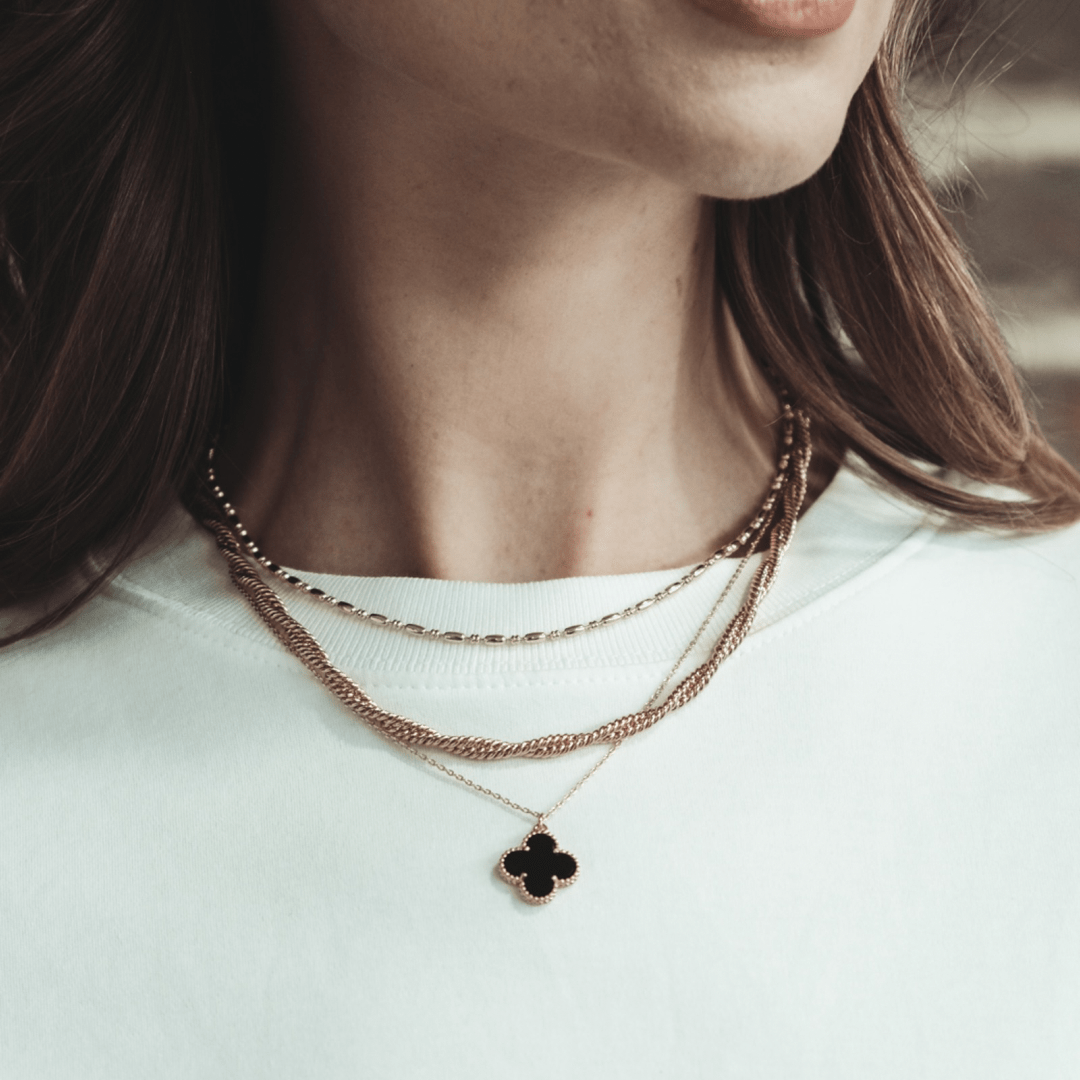 A woman wears three layered necklaces, the lowest with a Crossing Twisted Chain pendant.