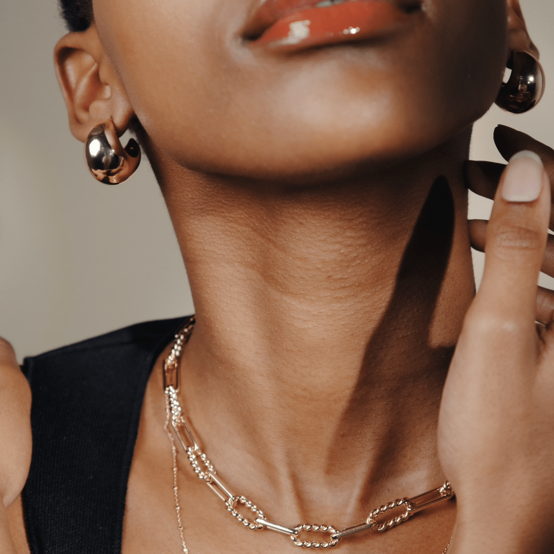 Close-up of a person with Twilight Moon Hoops and layered gold necklaces.