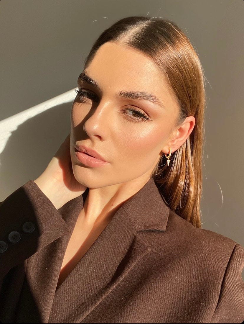 Woman in brown blazer with slicked-back hair, wearing Crystal Spear Drop Gold, in sunlight.