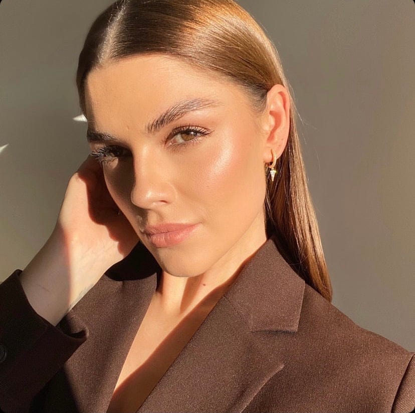 Close-up of a woman with sleek brown hair wearing a brown blazer and gold Crystal Spear Drop Gold earrings.