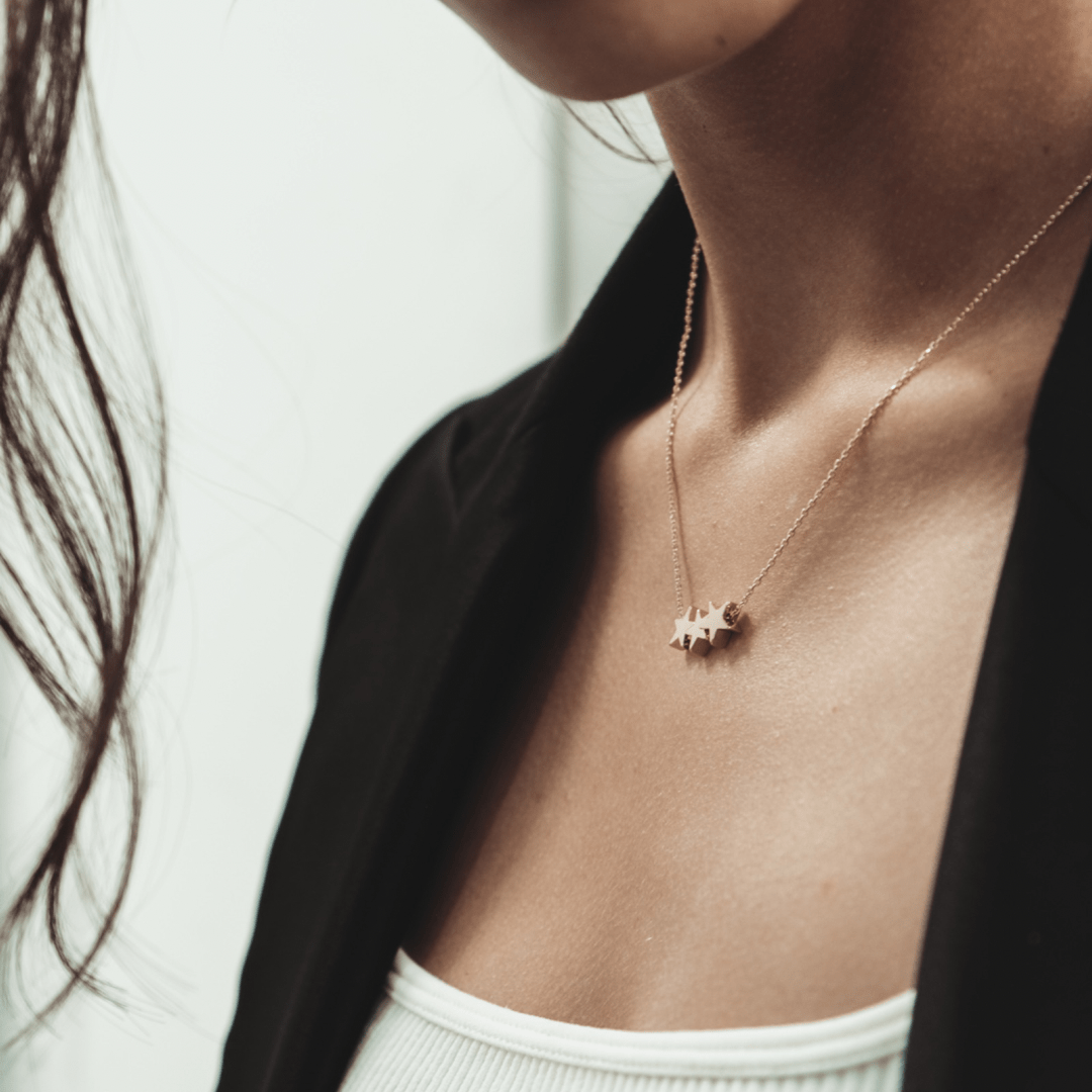 Woman wearing a Trio Star Charm Necklace and a black blazer.