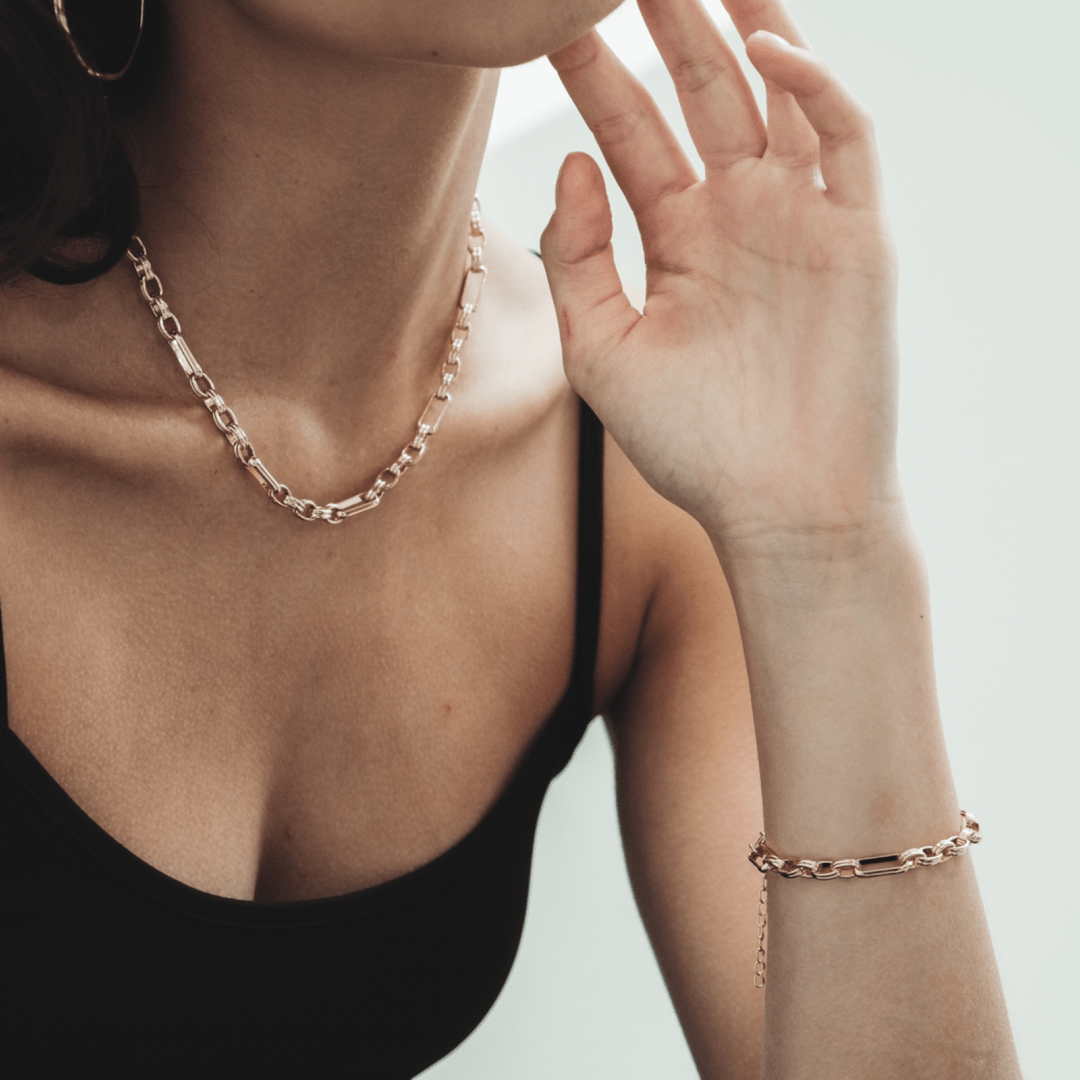 A person wearing a gold necklace and Triple Link Bracelet.