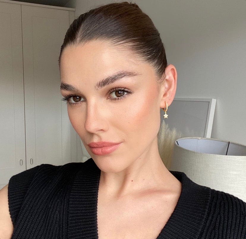 Close-up portrait of a woman with brown hair pulled back, wearing Moon and Star Diamante Huggie Silver earrings and a black top.