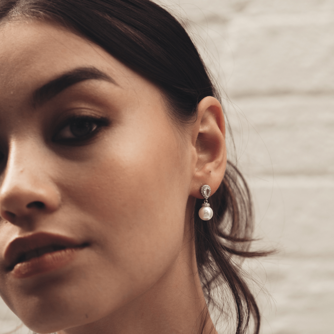 Close-up of a woman wearing a Bridal Silver Pear Teardrops earring.