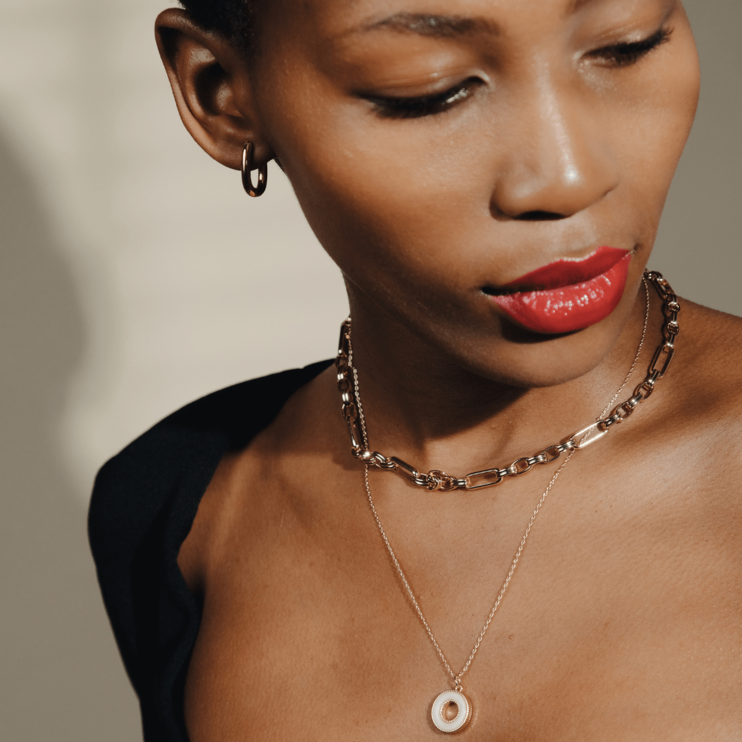 A woman with red lipstick wears gold jewelry, including Mini Square Gold Hoop earrings and two necklaces.