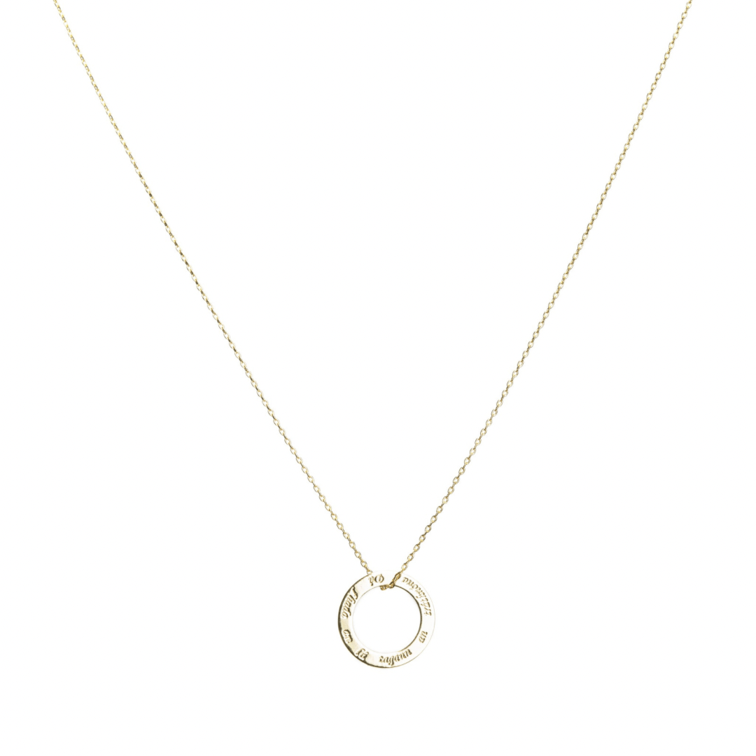 Gold delicate necklace chain with a circular pendant engraved with text.