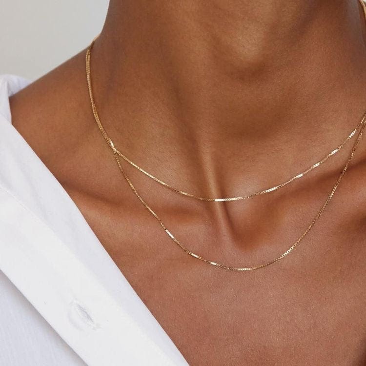 Close-up of a person wearing a Box Chain 14 inches and a delicate gold necklace.