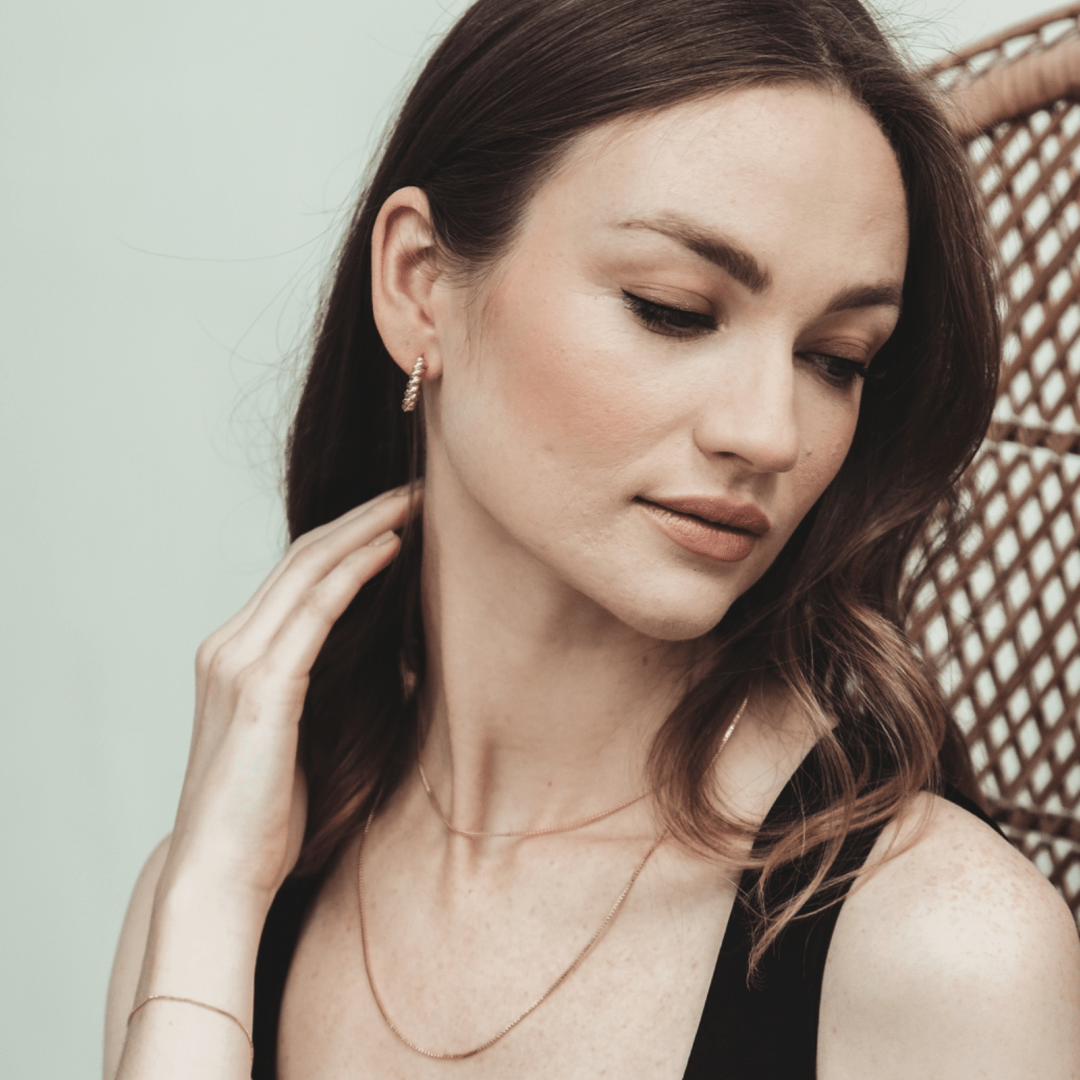 Woman with brown hair wearing Box Chain 14 inches jewelry looks down.