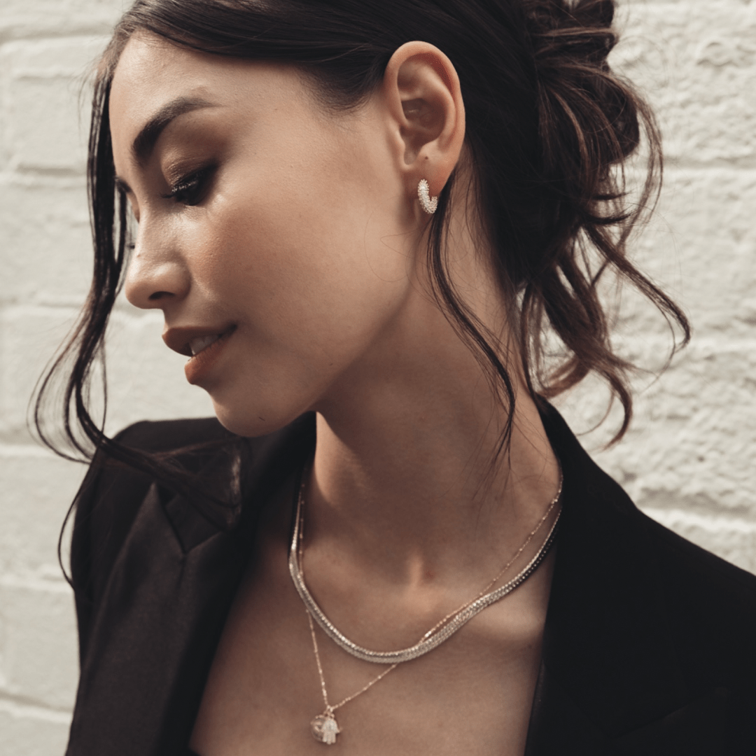 A woman in a black blazer wearing Evil Eye and Hamsa Hand jewelry.