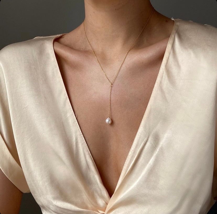Woman wearing a cream-colored top and a gold Bridal Pearl Drop Lariat necklace with a pearl pendant.