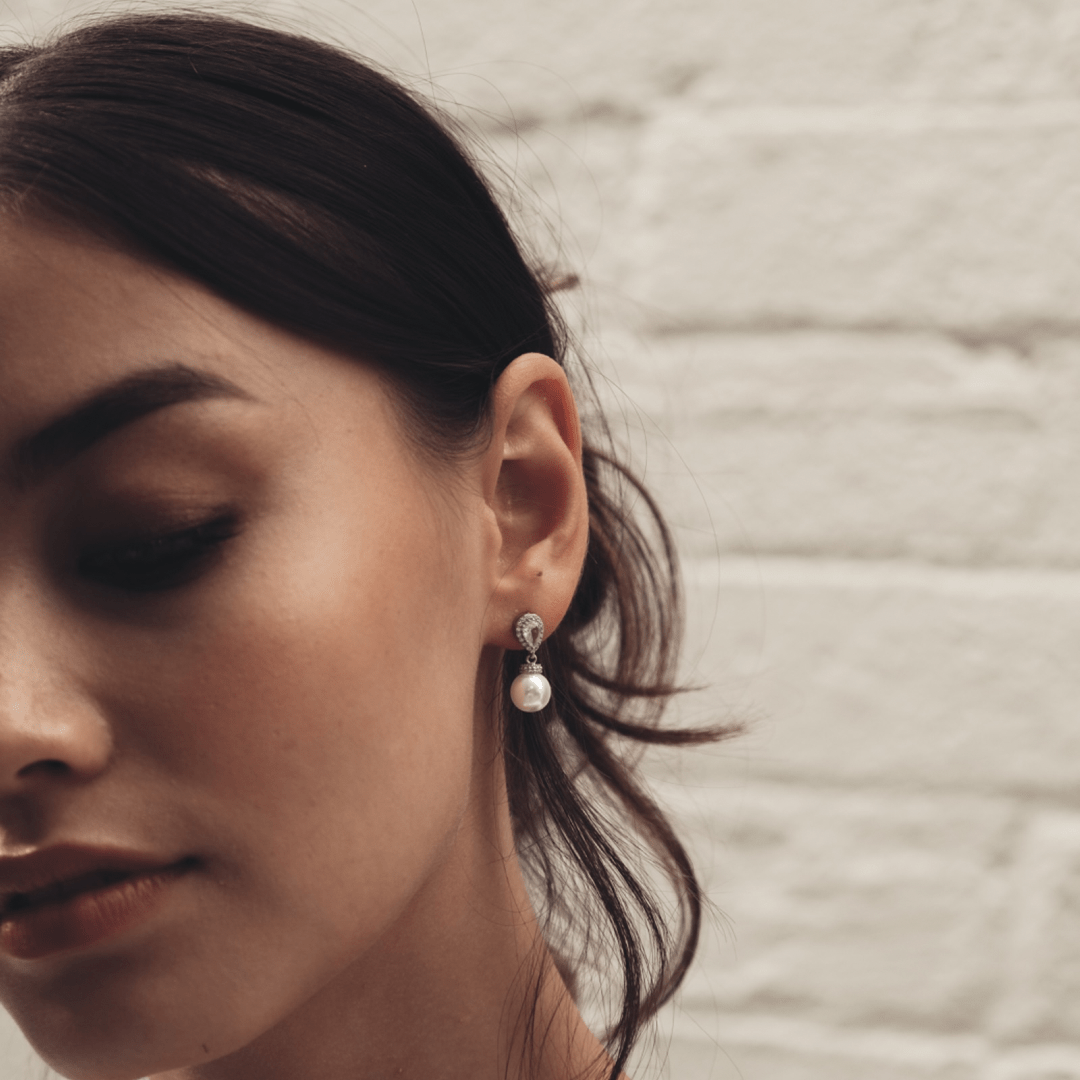 Woman with dark hair wearing a Bridal Silver Pear Teardrop earring.