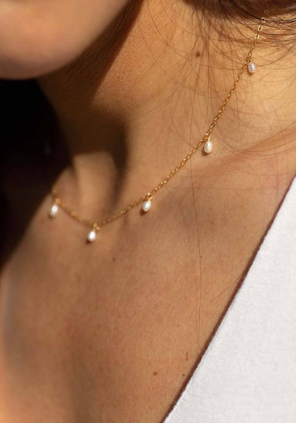 Close-up of a person wearing a Bridal Snow Drop Pearl necklace with dangling pearls.