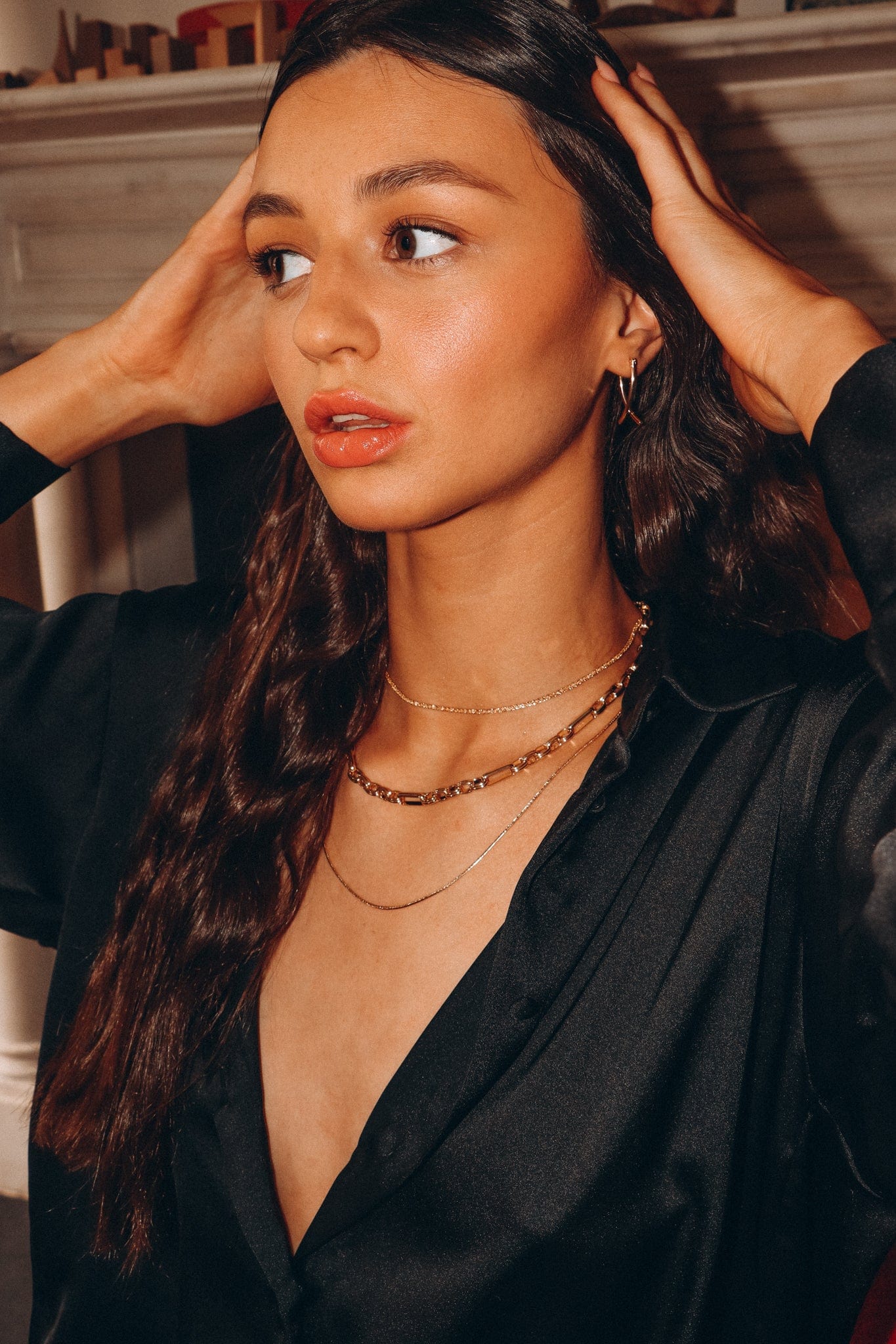 A woman with long brown hair and gold necklaces wears a black satin blouse with Box Chain 19 inches.