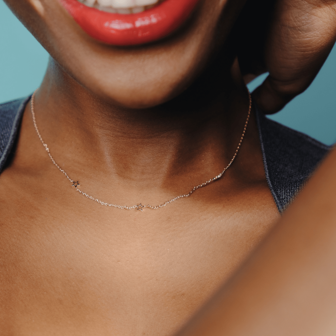 Close-up of a person with red lipstick wearing a Three Times A Charm Star Necklace.