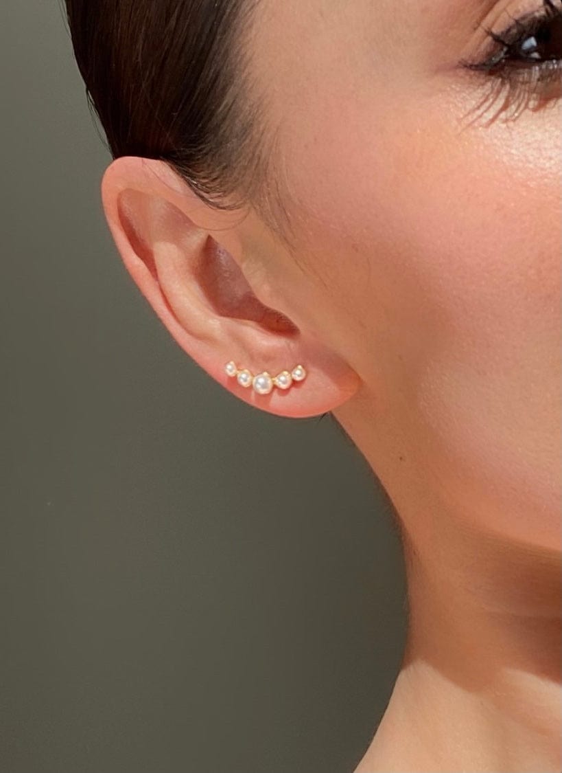 Close-up of a person's ear with a curved Bridal Pearl Bar Stud earring featuring five small pearls.