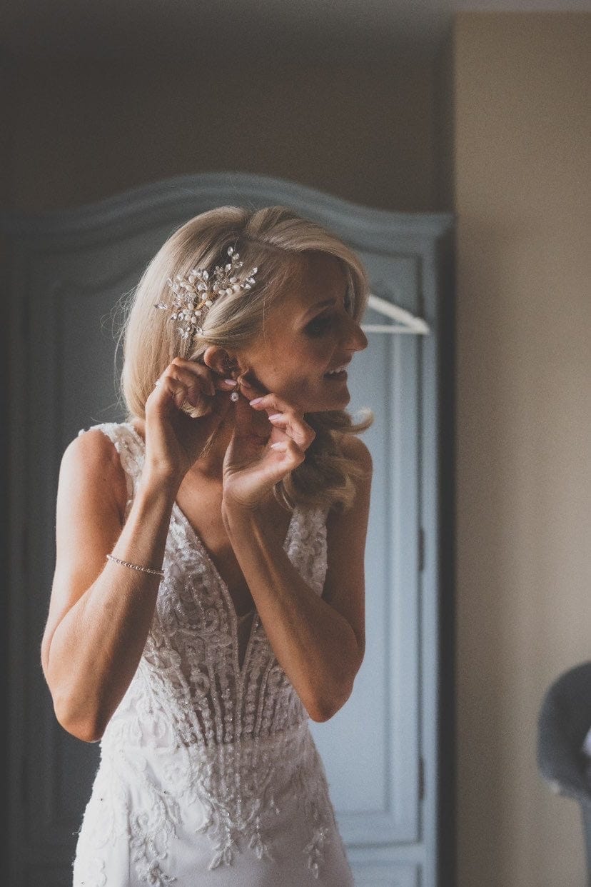 A woman in a wedding dress puts in a Bridal Snow Drop Pearl earring.