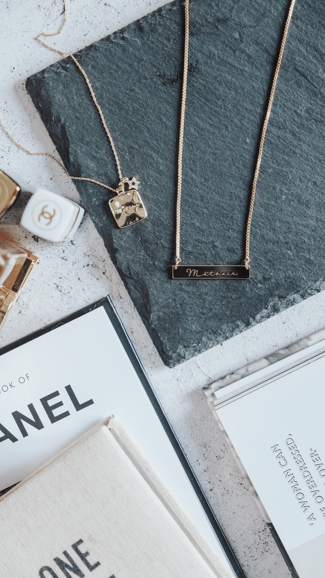A flat lay of M√°thair Star Disc Necklace jewelry and books.