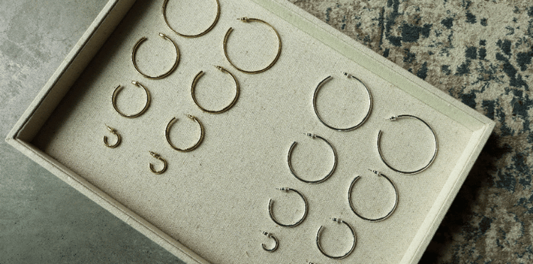 Close-up of a woman's ear with two gold hoop earrings.