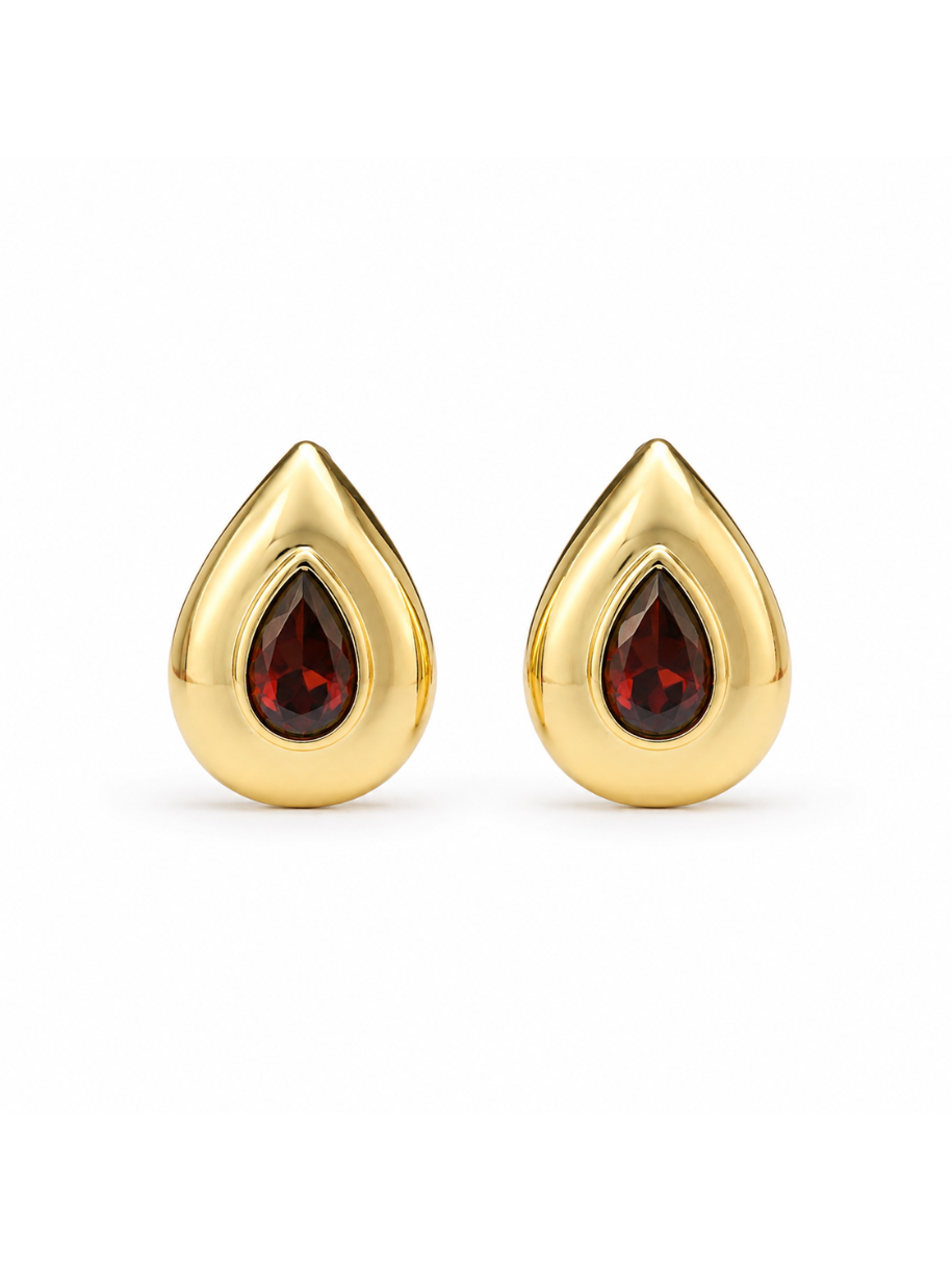 A close-up view of the Garnet Bezel Teardrop Earrings, showing the faceted garnet stone framed by a smooth gold bezel setting.