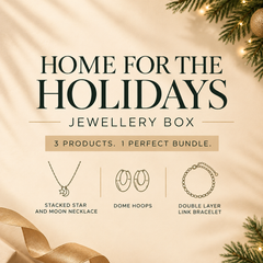 'Home for the Holidays Jewellery Box' featuring three jewelry items: a stacked star and moon necklace, dome hoops, and a double layer link bracelet, set against a warm beige background with holiday pine branches and a gold ribbon.